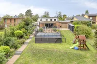 Frontale Gartenansicht mit Pool und großzügigen Terrassenbereichen