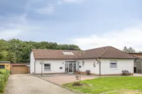 Westansicht mit drei separaten Eingängen sowie Garage und drei Kfz-Stellplätzen