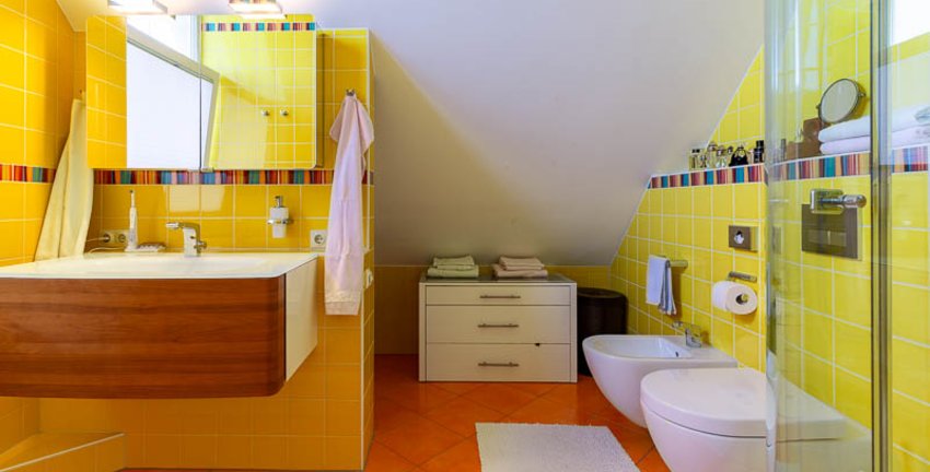 Bunt geflieste Wände für viele bunte Erinnerungen: das Badezimmer im Spitzboden erleichtert Ihren Alltag