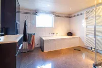 Geräumiges Badezimmer mit eleganter Badewanne, Handtuchständer und großem Fenster.