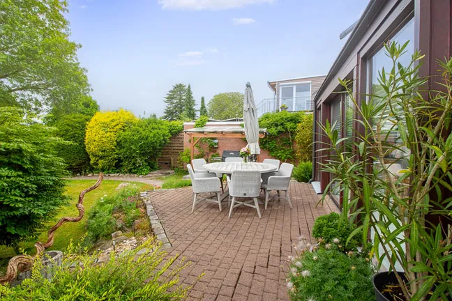 Die stilvolle Terrasse am Wintergarten bietet Raum für gesellige Abende und entspannte Stunden im Garten.