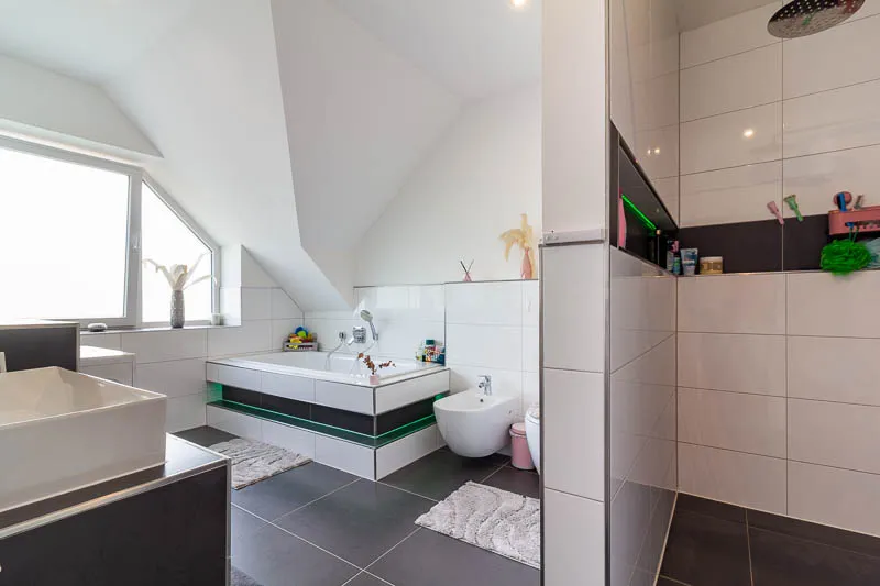 Elegantes Badezimmer mit klaren Linien, großformatigen Fliesen und stimmiger Lichtgestaltung.