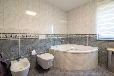 Helles Tageslichtbad mit stilvoller Eckwanne, Bidet und moderner Ausstattung – ein idealer Ort zum Entspannen.