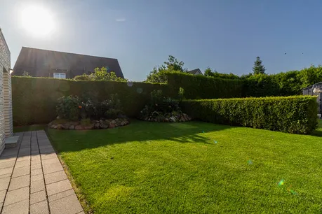 Pflegeleichter Garten mit blickdichtem Heckenzaun und liebevoll angelegten Beeten – perfekte Privatsphäre für erholsame Stunden im Grünen.
