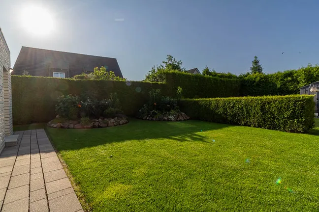 Pflegeleichter Garten mit blickdichtem Heckenzaun und liebevoll angelegten Beeten – perfekte Privatsphäre für erholsame Stunden im Grünen.