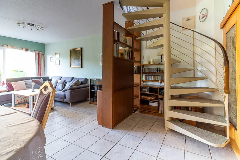 Elegante Wendeltreppe, die das offene Raumkonzept perfekt ergänzt und den Zugang zum Obergeschoss ermöglicht.