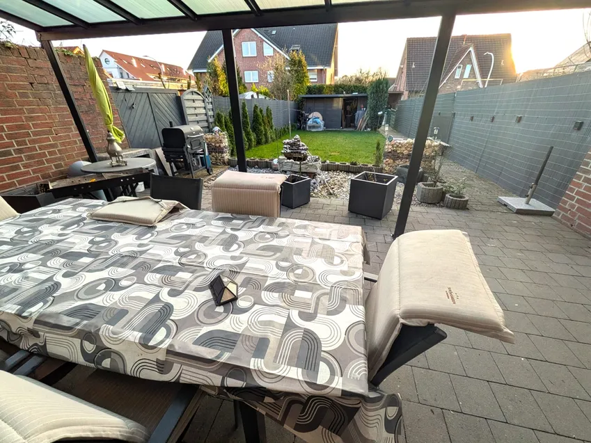 Großzügige Terrasse mit Gartenbereich und der dahinter liegenden Garage