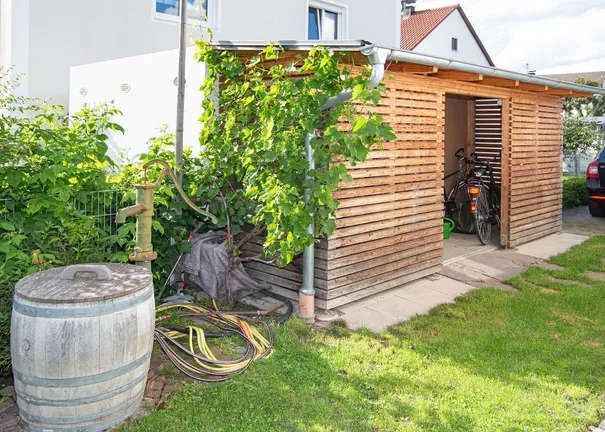 Holzlege und Gartenbrunnen