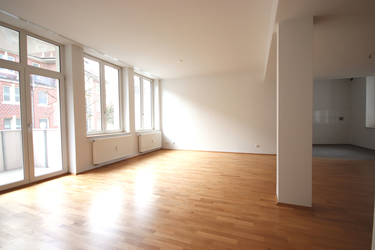 Das Wohnzimmer mit Zugang zum Balkon und großzügiger Fensterfront