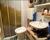 Kleines Badezimmer mit Abstellkammer hinter der Duschabtrennung