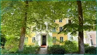 Hausansicht von der Straße im Sommer mit Baumgrün
